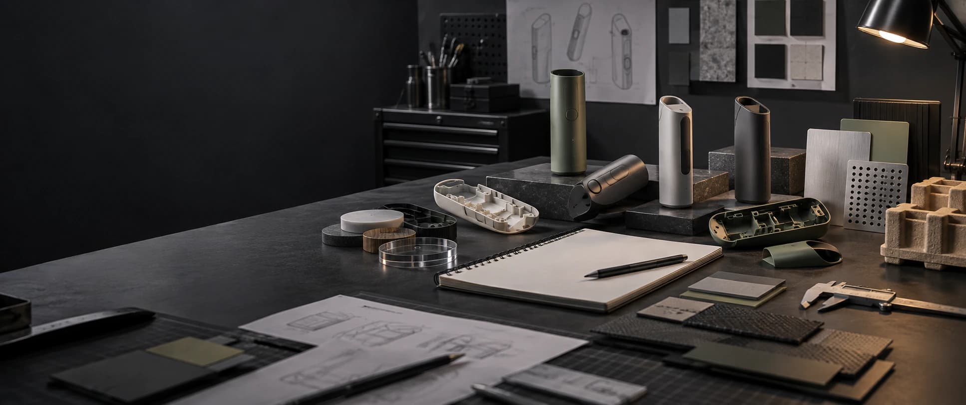 Hardware development workbench with anonymous device prototypes and material samples.
